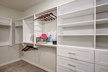 A walk in closet with white cabinets and shelves