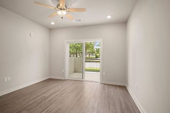 An empty living room with a ceiling fan and a door to a patio