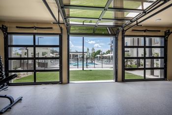 The view of the pool from inside an empty gym with glass doors