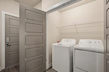 A laundry room with a washer and dryer and a closet with a door