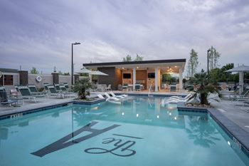 A swimming pool with lounge chairs and a building with a pool