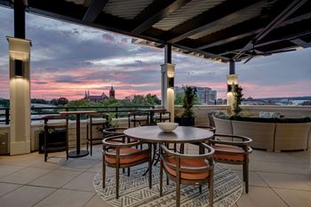 A terrace with tables and chairs overlooking a city at sunset