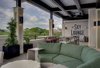A patio with a green couch and a view of the sky lounge