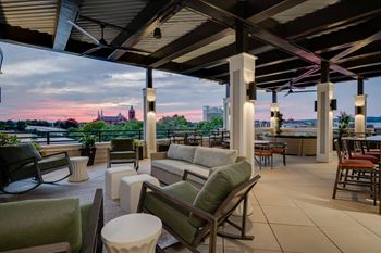 A patio with couches and chairs and a view of the river and a building