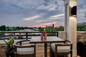 A balcony with a table and chairs and a bottle of wine on it