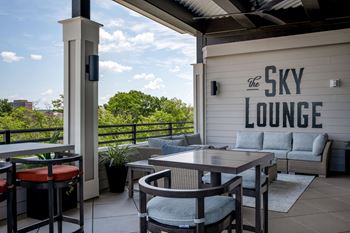 A patio with tables and chairs and a sky lounge sign