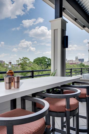 A balcony with a table and chairs and a bottle of whisky on it