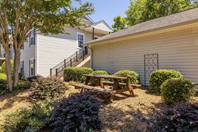Augusta townhouse for rent - A wooden picnic table is in the middle of a garden with a house in the background.