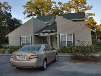 A beige toyota car is parked in front of a house