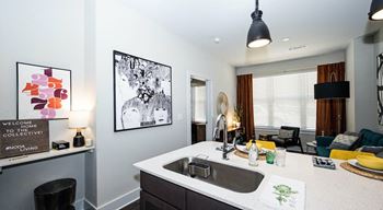 A kitchen with a white counter top and a black chair.