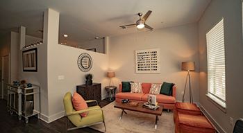 A living room with a green chair, a red ottoman, and a white wall with a circular design.
