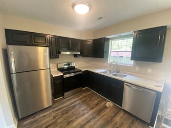 A kitchen with black cabinets and a stainless steel refrigerator