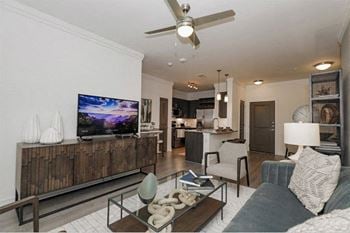 A modern living room with a flat screen tv and a ceiling fan