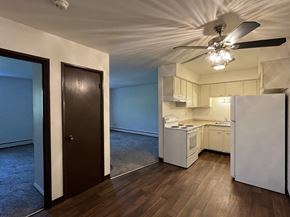 Milwaukee apartment for rent - an empty living room with a ceiling fan and a kitchen