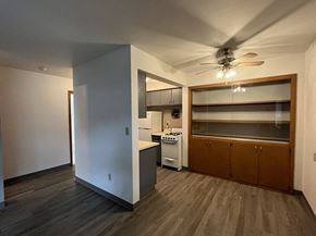 Milwaukee apartment for rent - an empty living room with a kitchen and a ceiling fan
