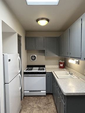 Milwaukee apartment for rent - A kitchen with a white refrigerator, a white sink, and a black stove top oven.