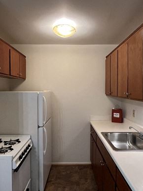 Milwaukee apartment for rent - A kitchen with a white fridge, white stove, and brown cabinets.