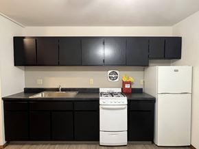 Milwaukee apartment for rent - A white stove and refrigerator in a kitchen with black cabinets.