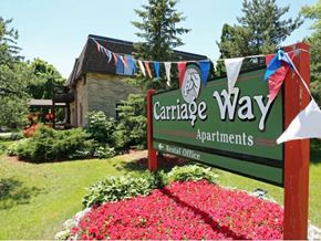 New Berlin apartment for rent - A sign for Carriage Way Apartments stands in front of a building with a garden in the foreground.