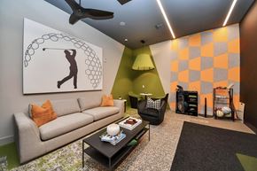 Spring apartment for rent - A gaming room with a couch, a coffee table, and a painting of a person playing golf.