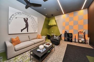 Spring apartment for rent - A living room with a couch, a coffee table, and a painting of a person playing golf.