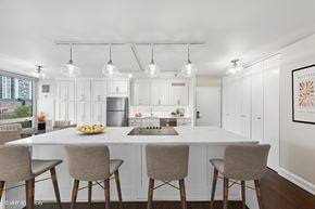 Chicago apartment for rent - a kitchen with white cabinets and a white counter top and chairs