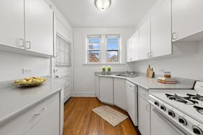 Chicago apartment for rent - a kitchen with white cabinets and a stove and a window