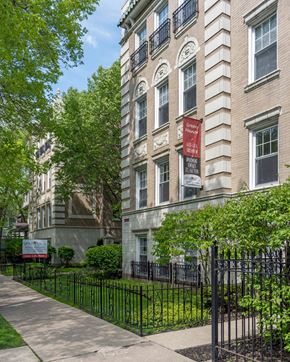 Chicago apartment for rent - an apartment building with a black iron fence and a red sign on the side of the building
