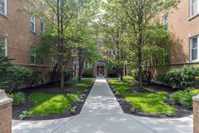 Chicago apartment for rent - a walkway with trees and grass in front of an apartment building