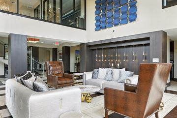 Des Peres apartment for rent - A modern living room with a white couch, a brown leather chair, and a blue abstract painting on the wall.
