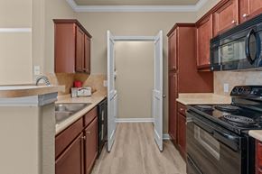 San Antonio apartment for rent - A kitchen with brown cabinets and a black stove top oven.