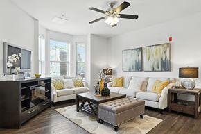 O'fallon apartment for rent - A living room with a white couch, a coffee table, and a ceiling fan at Bramblett Hills Luxury Apartments in O Fallon MO 63366