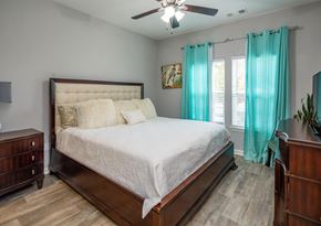 Murfreesboro apartment for rent - A bedroom with a large bed, a ceiling fan, and a dresser.