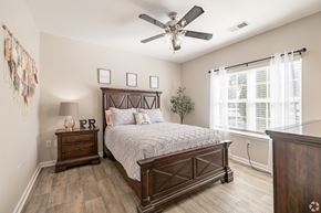 Goodlettsville apartment for rent - A bedroom with a large bed, a wooden dresser, and a ceiling fan.