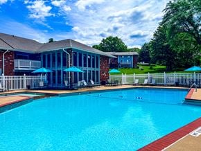 St. Louis apartment for rent - A large swimming pool in front of a house with a deck and umbrellas.
