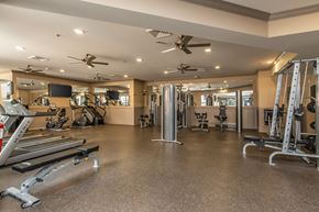 St. Louis apartment for rent - A spacious gym with a variety of equipment including treadmills, weight machines, and a television.