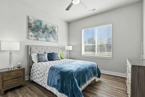 Weldon Springs apartment for rent - A bedroom with a bed, nightstand, and a painting on the wall.