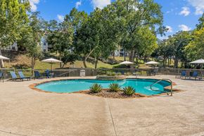 New Braunfels apartment for rent - A sparkling pool surrounded by trees and chairs.