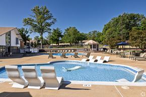 St. Louis apartment for rent - A pool with white chairs and a building in the background.