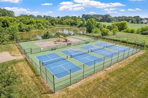 Hudsonville townhouse for rent - A tennis court surrounded by a green fence with a playground in the background.