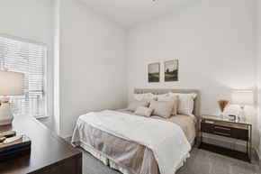 Dallas apartment for rent - A bedroom with a large bed and a nightstand with a lamp at Everra Midtown Park Apartments, Dallas