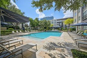 Dallas apartment for rent - A pool surrounded by sun loungers and umbrellas at Everra Midtown Park Apartments, Dallas