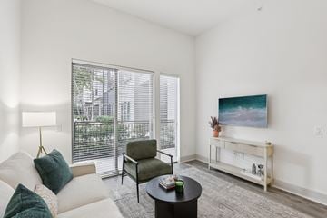Dallas apartment for rent - A living room with a white couch, a green chair, a coffee table, and a painting on the wall.