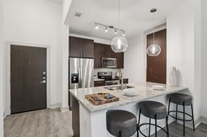 Dallas apartment for rent - A modern kitchen with a granite countertop and stainless steel appliances at Everra Midtown Park Apartments, Dallas, TX, 75231