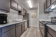 Cleburne apartment for rent - Galley kitchen with stainless appliances and gray cabinets at Arbors Of Cleburne Apartments, Cleburne, TX