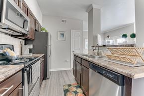 Dallas apartment for rent - A kitchen with a black fridge and a black stove top oven. at The Brazos, Dallas, TX