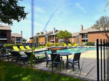Mesquite apartment for rent - A pool surrounded by chairs and tables in front of a building.