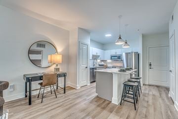 Dallas apartment for rent - A kitchen with a bar stool and a table with a chair.