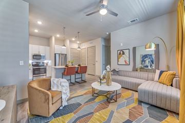 Grapevine apartment for rent - A living room with a brown chair and a yellow pillow on a grey couch.