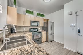 Dallas apartment for rent - A kitchen with a stove top oven, microwave, and refrigerator.